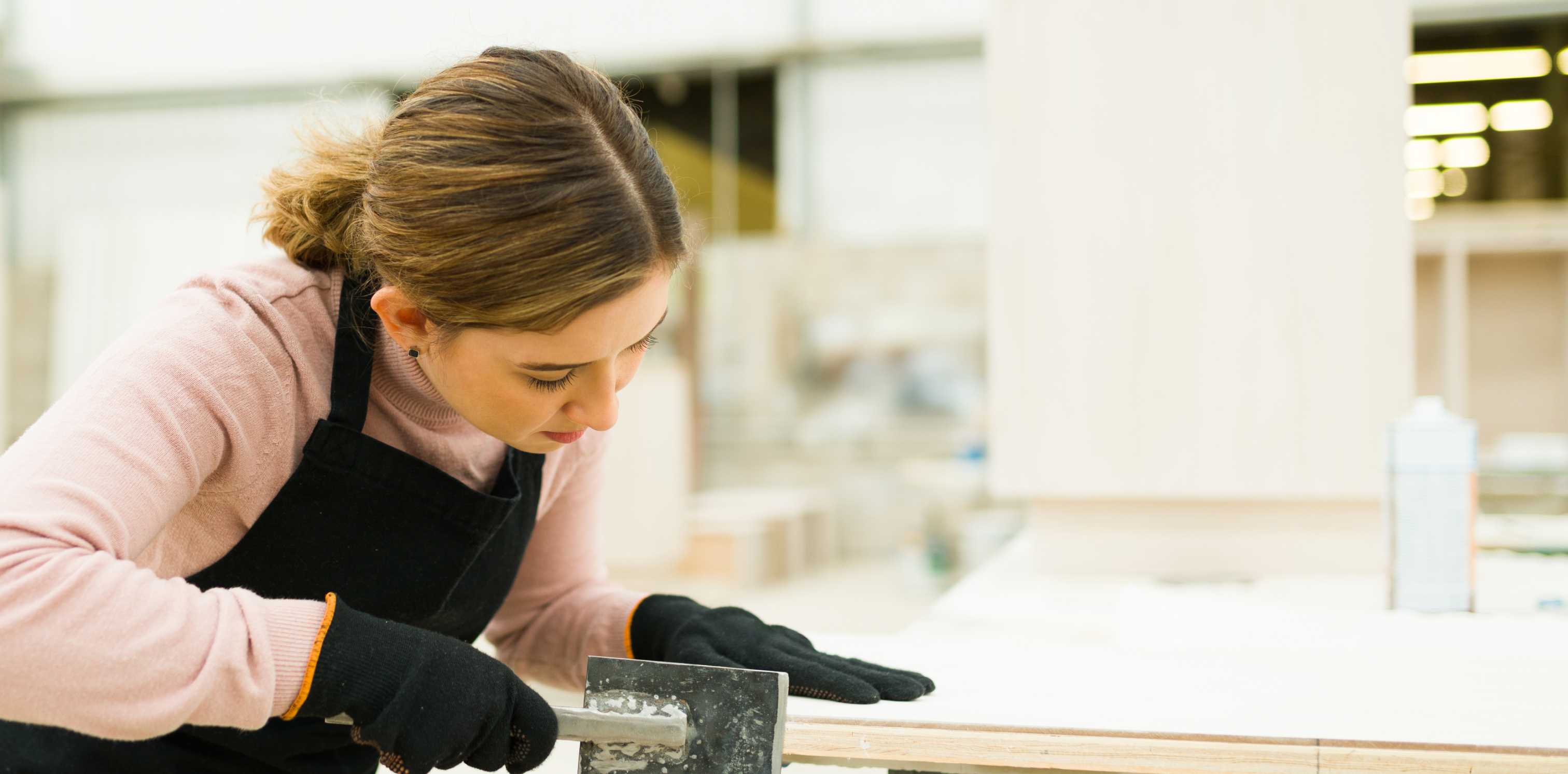 woman sanding partially finished wooden cabinet